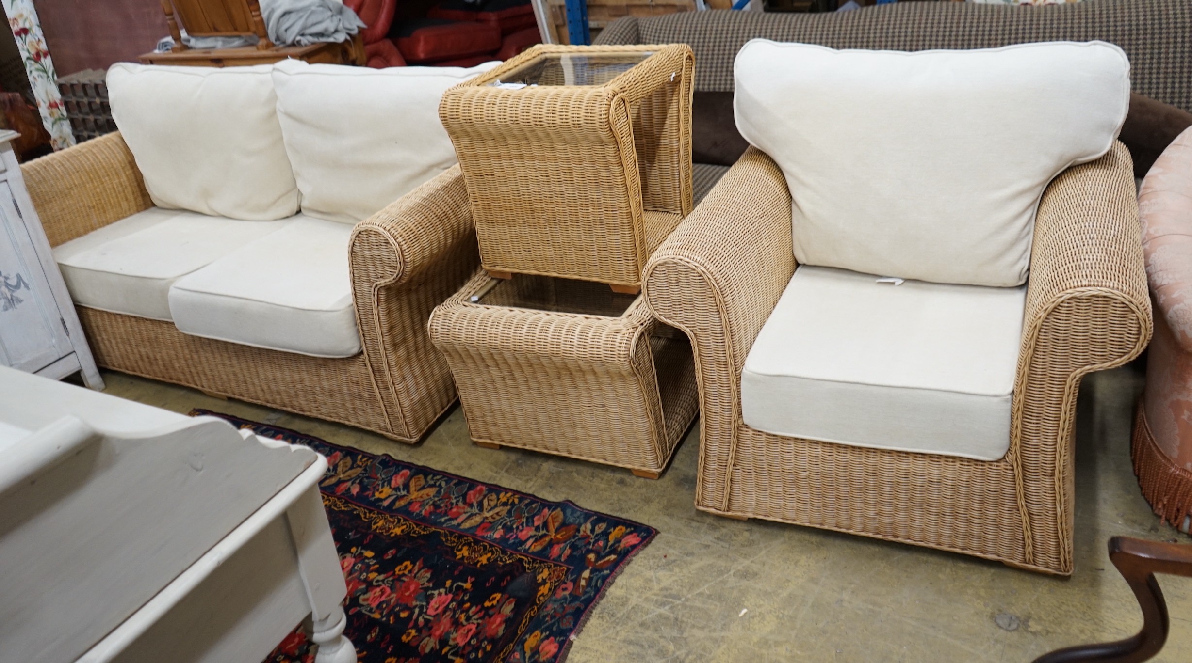 A contemporary rattan and natural fabric four piece conservatory suite, comprising settee, length 180cm, depth 86cm, height 85cm, armchair and two glass top tables